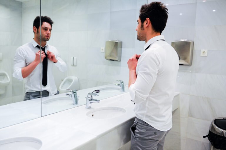 Man getting dressed in a public restroom with mirror